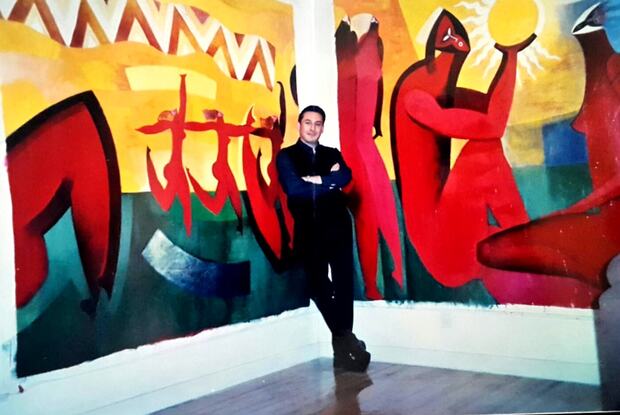 El artista de pie ante un mural suyo de gran formato